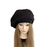 Black beret with pink speckles on a mannequin head against a white background