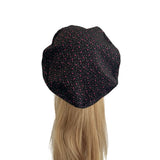 Black beret with red speckles on a mannequin head against a white background