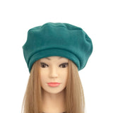 Teal beret on a mannequin head with long brown hair against a white background