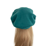Teal beret on a mannequin head with blonde hair against a white background