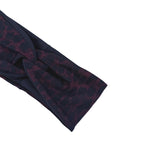 A close-up of a dark navy blue fabric accessory, possibly a headband or strap, featuring a textured, embossed pattern in a deep burgundy or maroon color, set against a plain white background.
