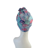Colorful shell-patterned headscarf on a mannequin head against a white background