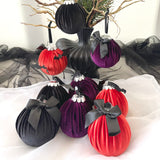 Decorative velvet baubles with black ribbons on a white surface.
