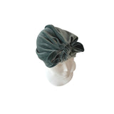 Green velvet turban on a mannequin head against a white background
