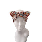 A multicolor floral bow headwrap displayed on a white mannequin head against a plain white background.