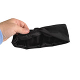 A hand holding a black satin headband against a plain white background.