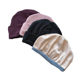 Four beanies in different colors on a white background