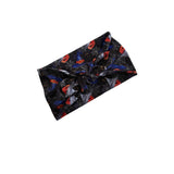 A black fabric headband with a twisted front, featuring a Halloween print of orange jack-o'-lanterns, spiderwebs, and bats, shown on a plain white background.
