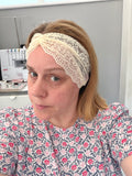 Woman wearing a floral dress and lace headband in a sewing room.