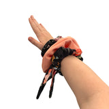Hand wearing a floral scrunchie on a white background