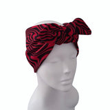 A red and black zebra-print fabric headband with a large bow, displayed on a white mannequin head against a plain white background.