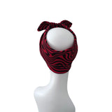 A red and black wavy patterned headband with a bow, displayed on a white mannequin head against a plain white background.