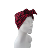 A red and black wavy patterned fabric headwrap styled on a white mannequin head, shown against a plain white background.